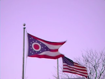 2 flags fluttering in the wind, one of which is the Ohio state flag and the other is the U.S. flag